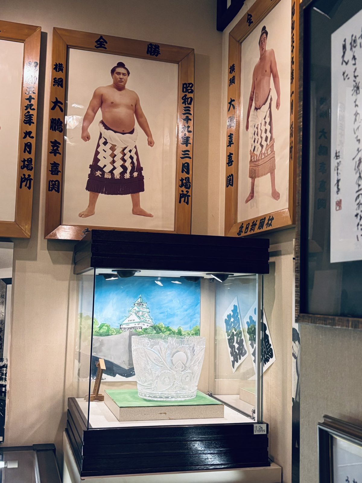 横綱・大鵬幸喜の額入り肖像とクリスタルのトロフィーがある記念館展示