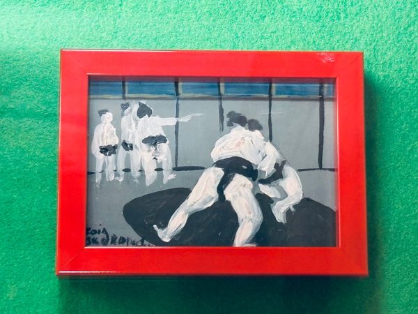 赤い額の絵画。稽古場で組み合う二人の力士と、それを見守る力士たち。署名入り