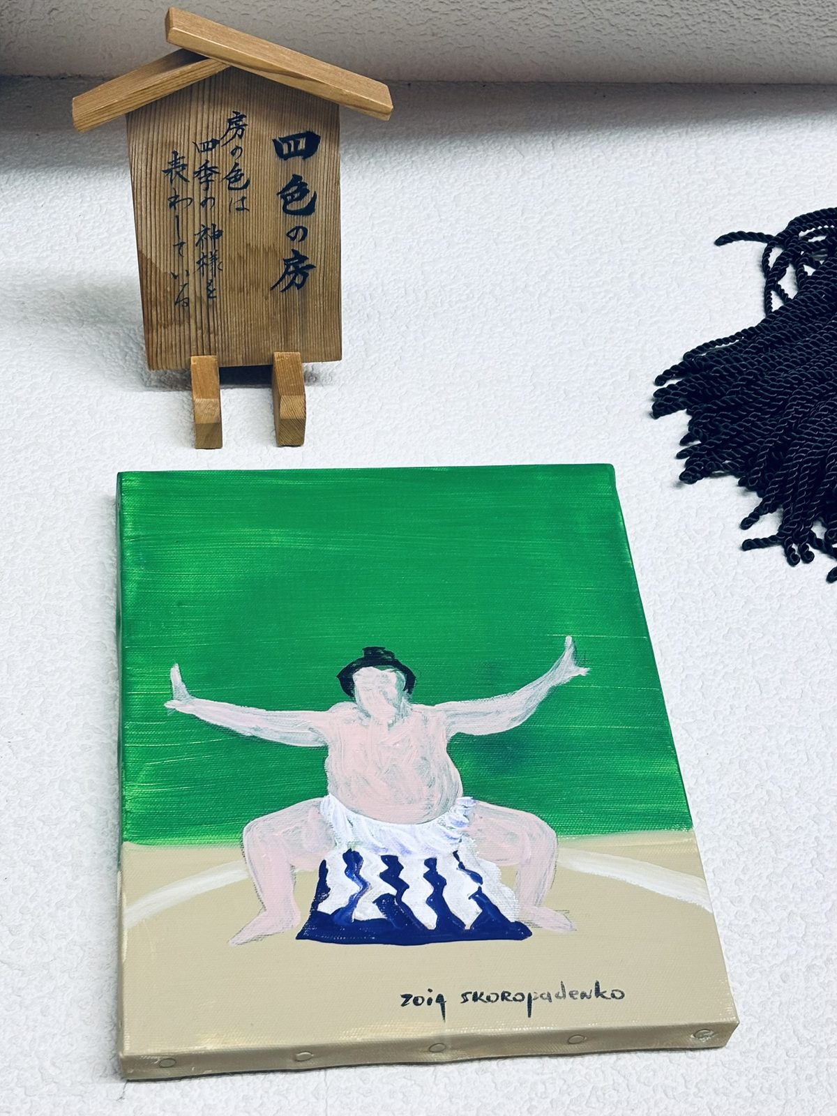 緑の地に綱を着けた横綱の絵画