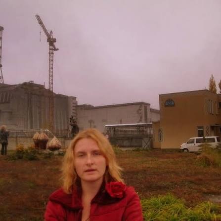チェルノブイリ原子力発電所を背に立つゾヤ・スコロパデンコ